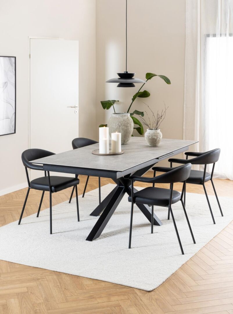 Eettafel met vier Ava eetkamerstoelen met armleuning (set van 2) op een wit vloerkleed.