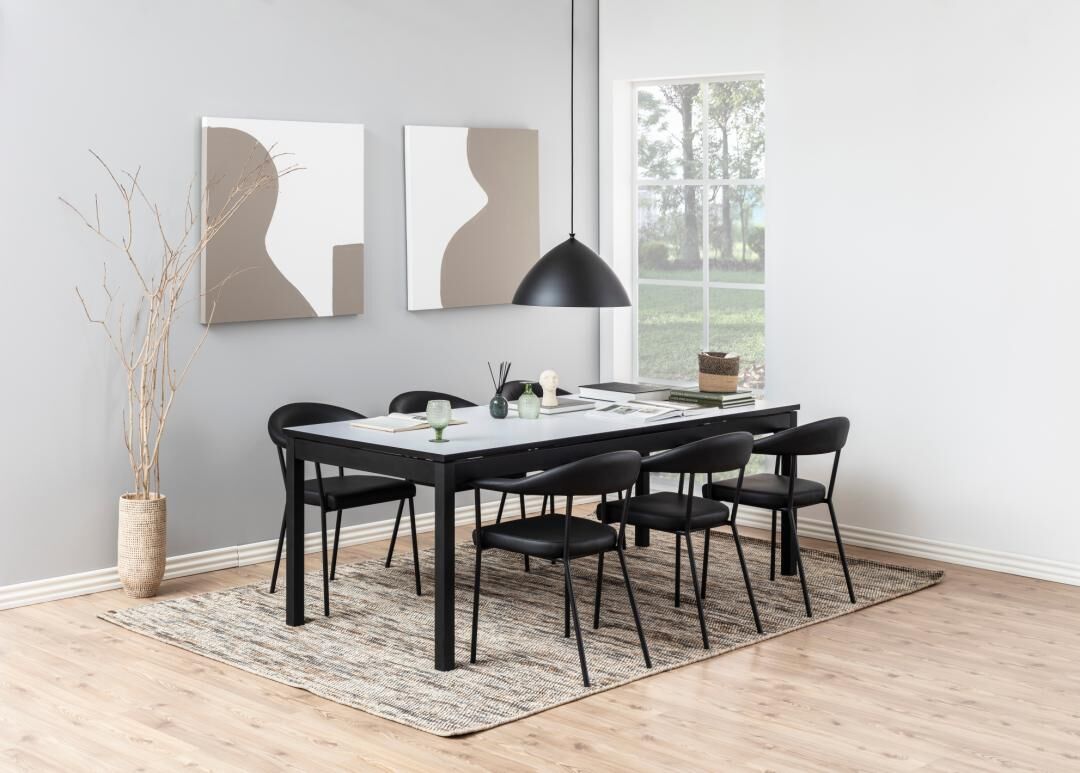 Dining table with six black chairs, rug, and modern decor Ava eetkamerstoel met armleuning (set van 2) Eetkamer met zwarte Ava eetkamerstoelen (set van 2) rond een tafel, met modern decor en een vloerkleed.
