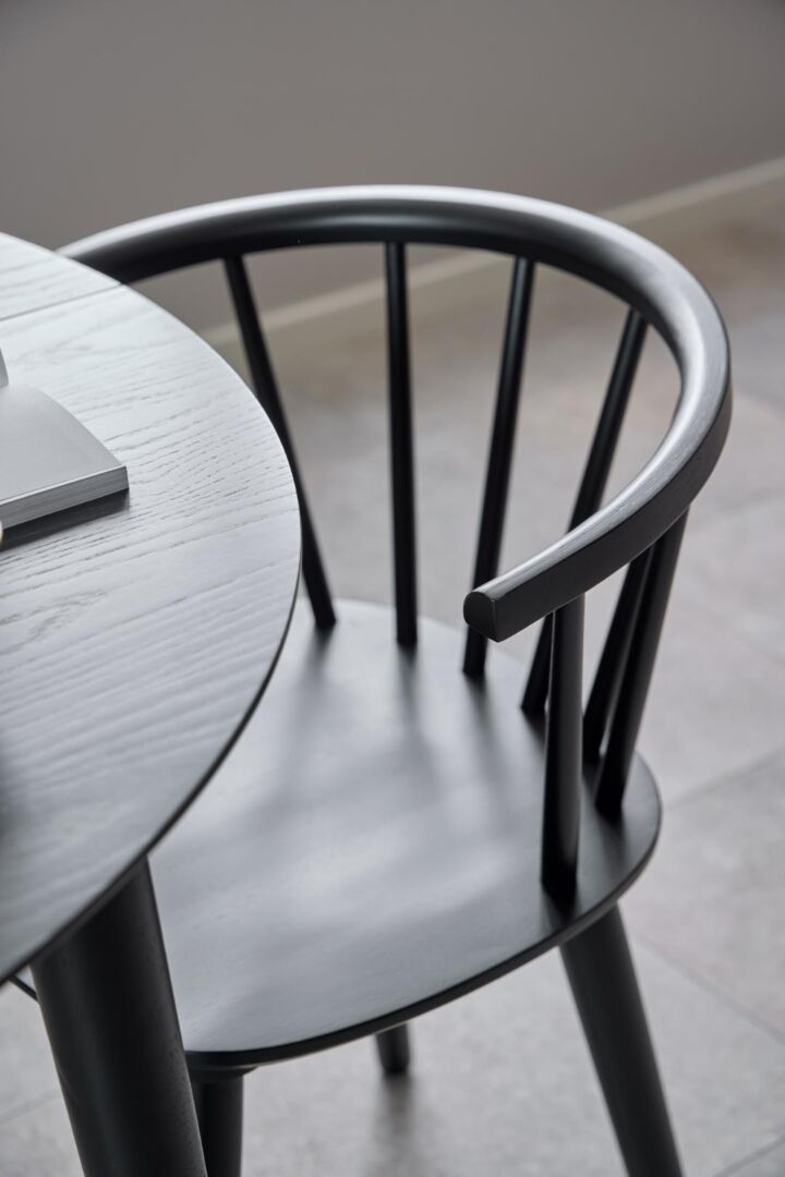 Ida eetkamerstoel: zwarte houten stoel met ronde rugleuning en zitting naast een ronde tafel.