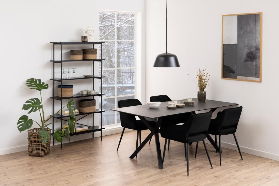 Eetkamer met zwarte tafel, vier Ranja eetkamerstoelen met armleuning, zwarte stellingkast en een monstera plant.