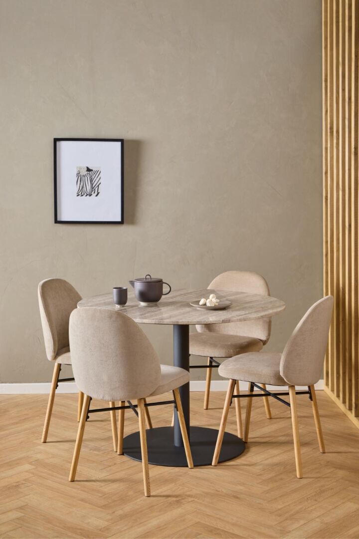 Ronde eettafel met vier Sophia eetkamerstoelen, beige bekleding en houten poten.