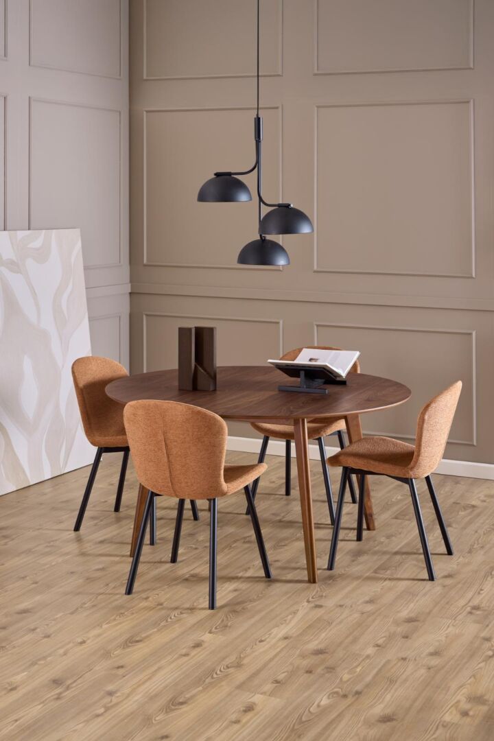 Ronde houten eettafel met vier oranje stoelen, inclusief Esra eetkamerstoel (set van 2), en zwarte hanglamp.