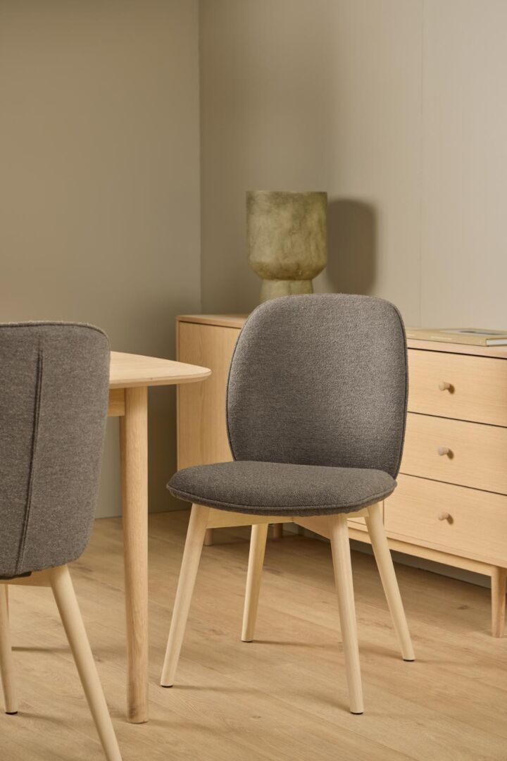 Cindy eetkamerstoel: Grijze stoffen stoel met houten poten, onderdeel van een set van 2 eetkamerstoelen.