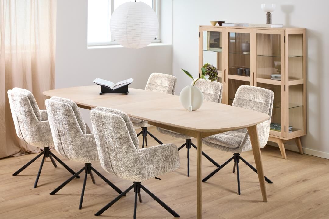 Eetkamer met ovale tafel en zes Edgar eetkamerstoelen met armleuning en zwarte poten.