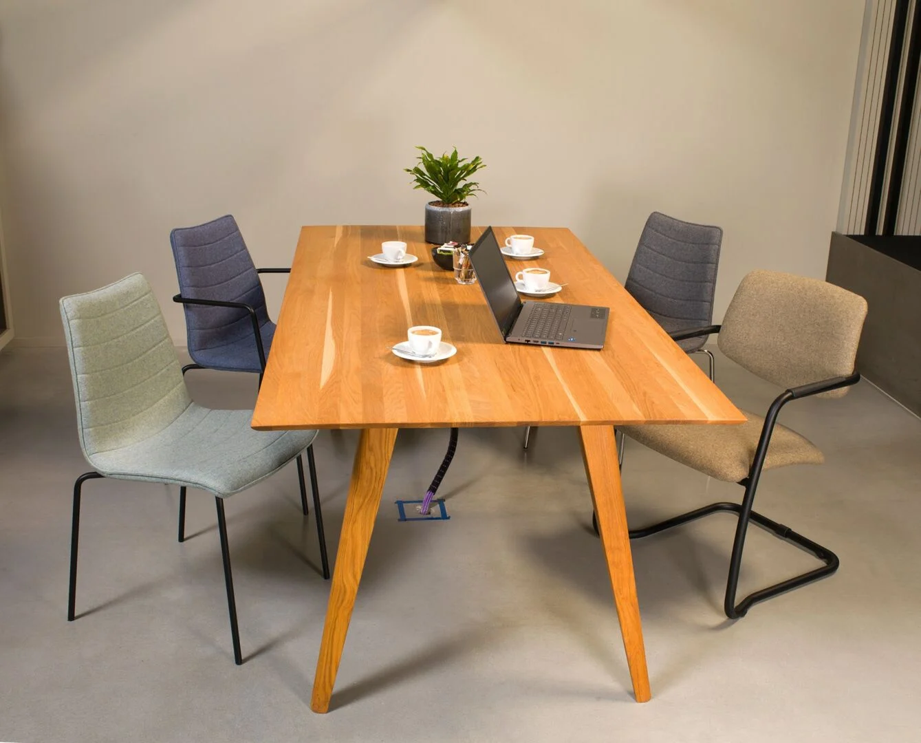 Houten tafel met vier stoelen, laptop, plant en vier kopjes. Workliving Verona Stoel Roze Wolvilt | Nieuwe Sfeer.