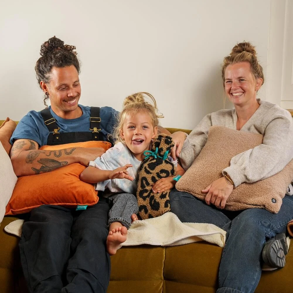 Gelukkige familie zit op een olijfgroene bank met kussens: Een vleugje luxe en comfort in je interieur.