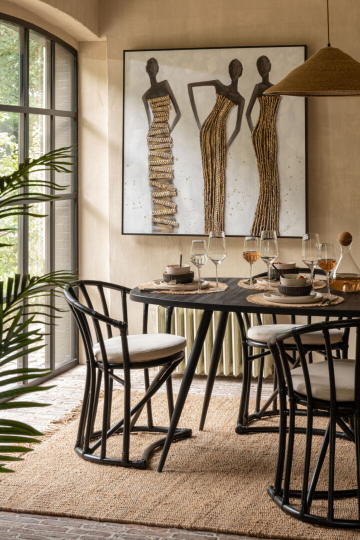 Eetkamerstoel Rotan Zwart met Wit Kussen van Nieuwe Sfeer aan een ronde eettafel.