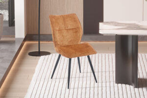 Eetkamerstoel Faye Goud Stof: Gouden stoffen stoel met zwarte poten op een vloerkleed.