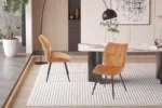 Eetkamerstoel Faye Goud Stof: Gouden velvet eetkamerstoelen met zwarte poten op een wit vloerkleed.