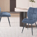 Eetkamerstoel Faye Blauw Stof: Blauwe stoffen eetkamerstoel met zwarte metalen poten op een gestreepte vloerkleed.