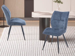 Eetkamerstoel Faye Blauw Stof: Blauwe stoffen eetkamerstoel met zwarte metalen poten op een gestreepte vloerkleed.
