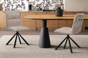 Stoel Jack Draaibaar Zand Stof van Nieuwe Sfeer: draaibare zandkleurige stoel aan een houten tafel.