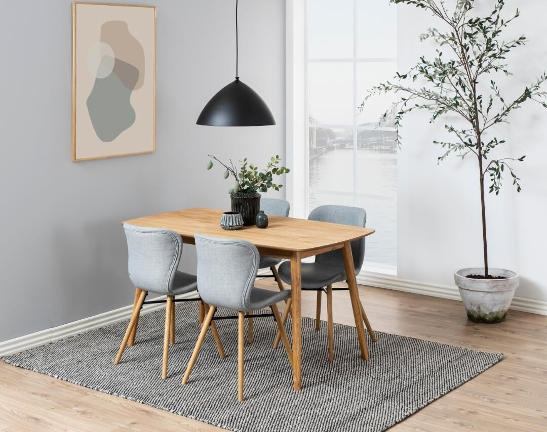 Eetkamer met houten tafel, grijze Batilda -A1 eetkamerstoelen (set van 2), vloerkleed en kunst aan de muur.