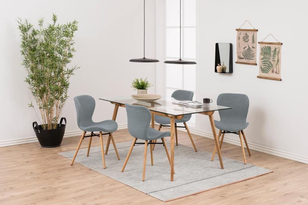 Eetkameropstelling met glazen tafel en vier blauwe Batilda -A1 eetkamerstoelen.