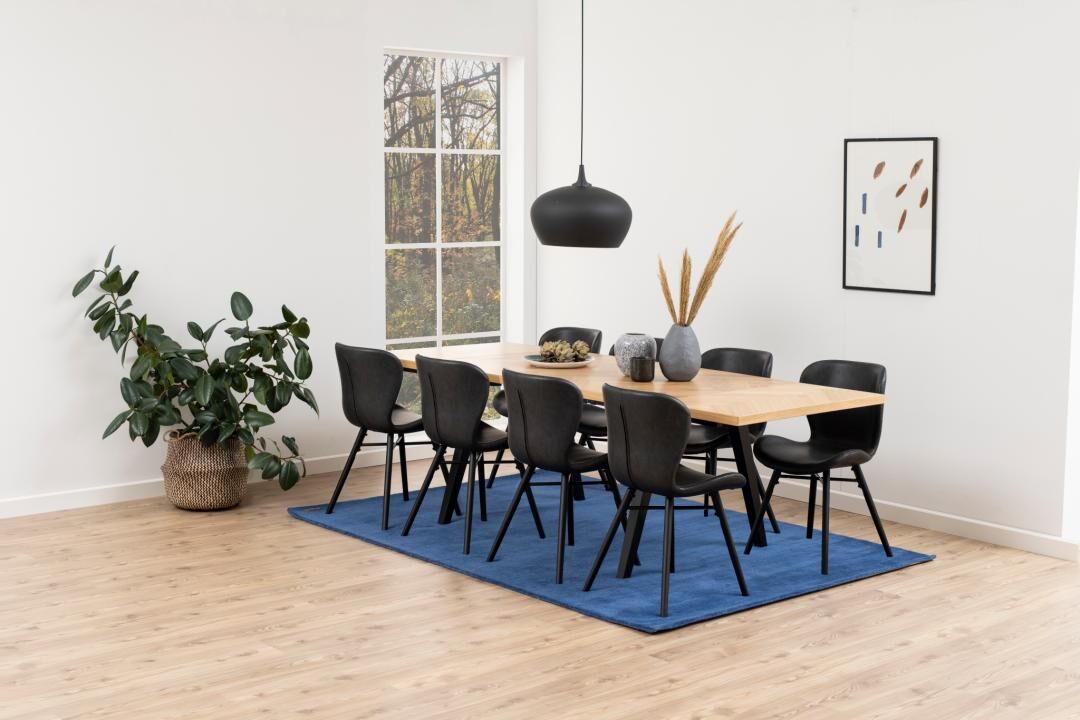 Eetkamer met houten tafel, blauw vloerkleed en Batilda -A1 eetkamerstoelen (set van 2) in zwart.