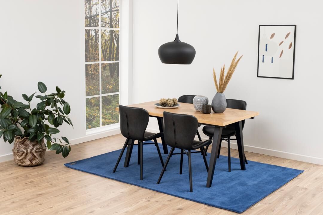 Batilda -A1 eetkamerstoel (set van 2) aan een houten eettafel met blauw vloerkleed.