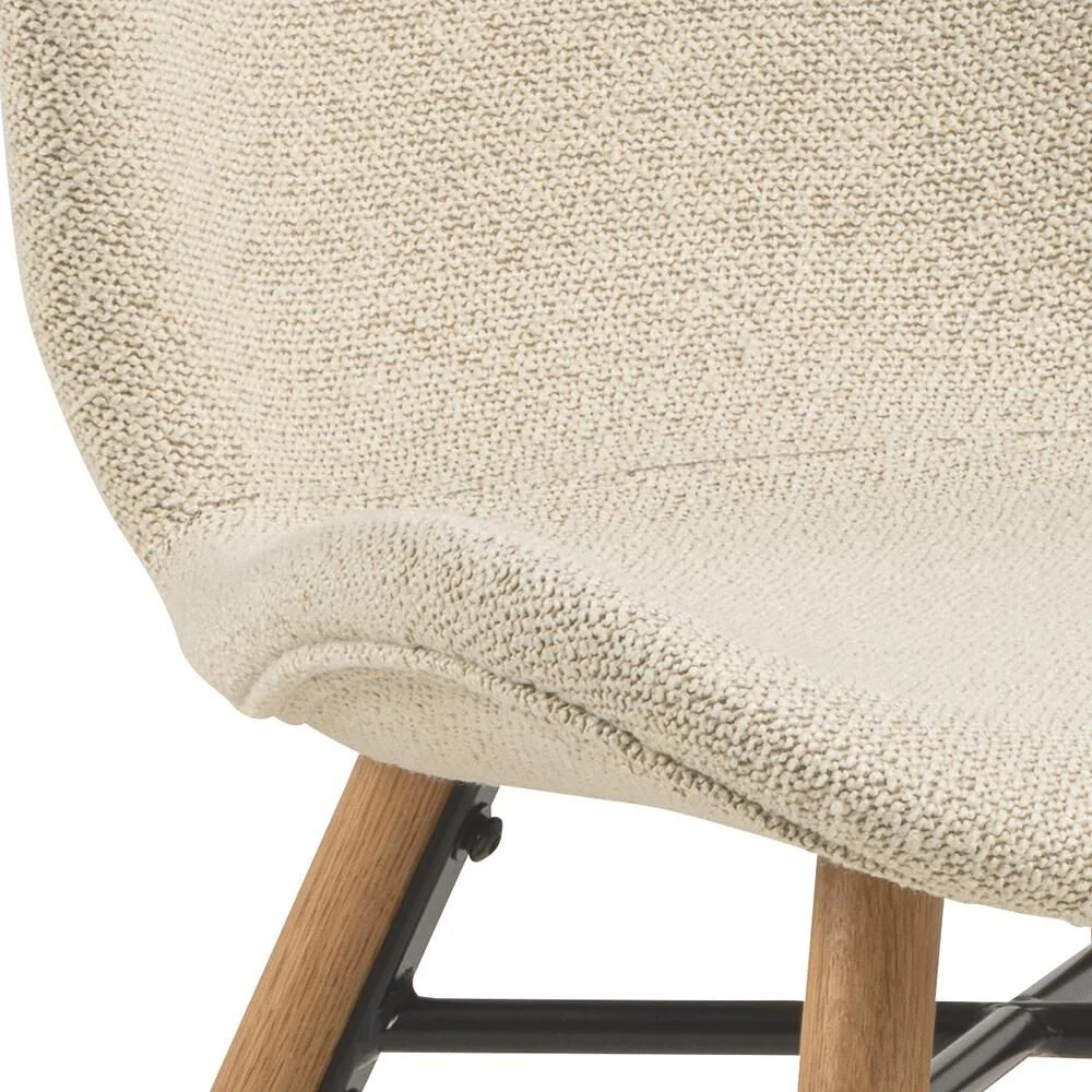 Close-up Batilda -A1 eetkamerstoel: beige stoffen zitting, houten poten, zwart metalen frame.