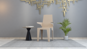 Piramidestoel Design Metaal | Nieuwe Sfeer: Stijlvolle stoel met bijzettafel en plant tegen een grijze achtergrond.