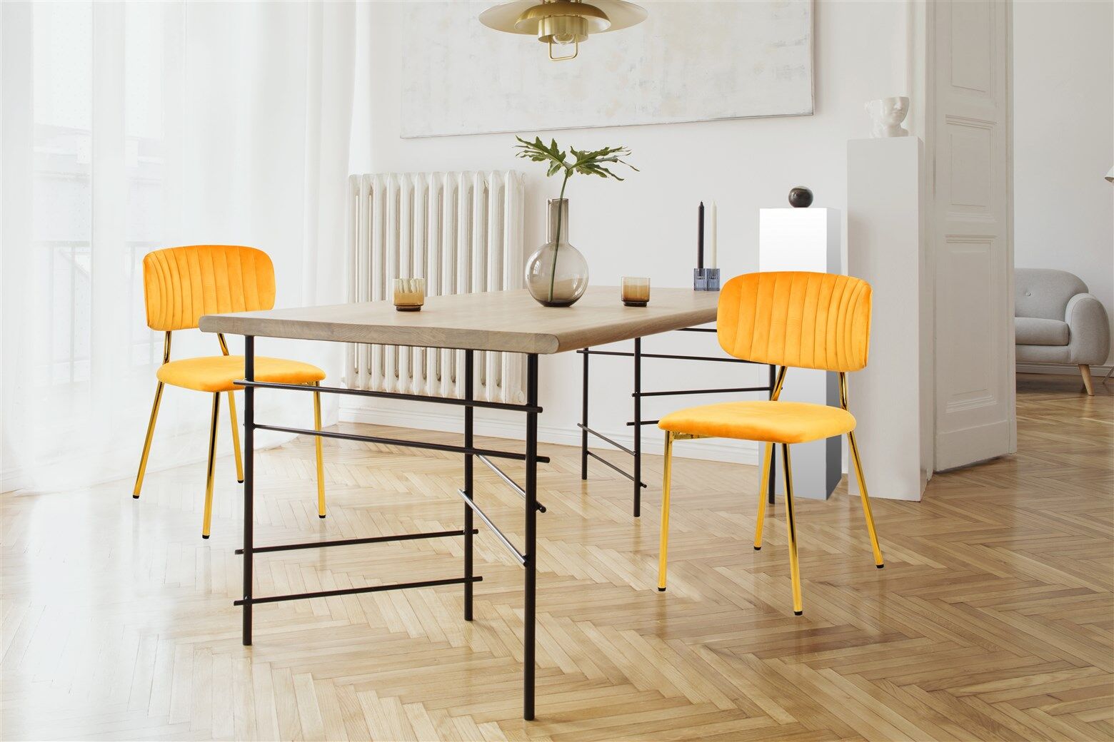 Stoel Kian 100 Lichtoranje Set van 2: Lichtoranje velvet stoelen aan een houten eettafel met zwart metalen poten.