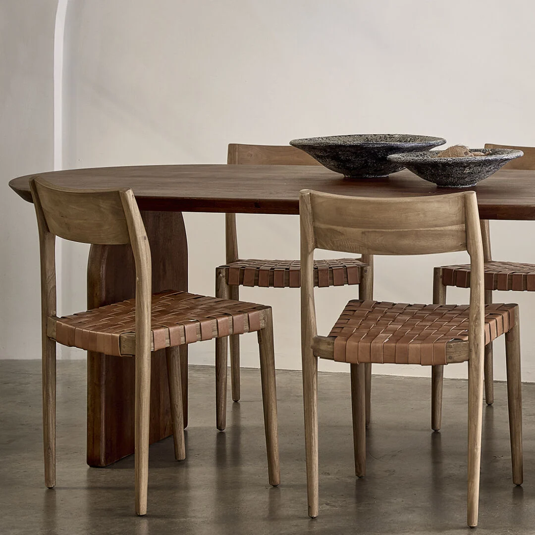 Freya teakhouten eetkamerstoel met leren zitting aan houten tafel.