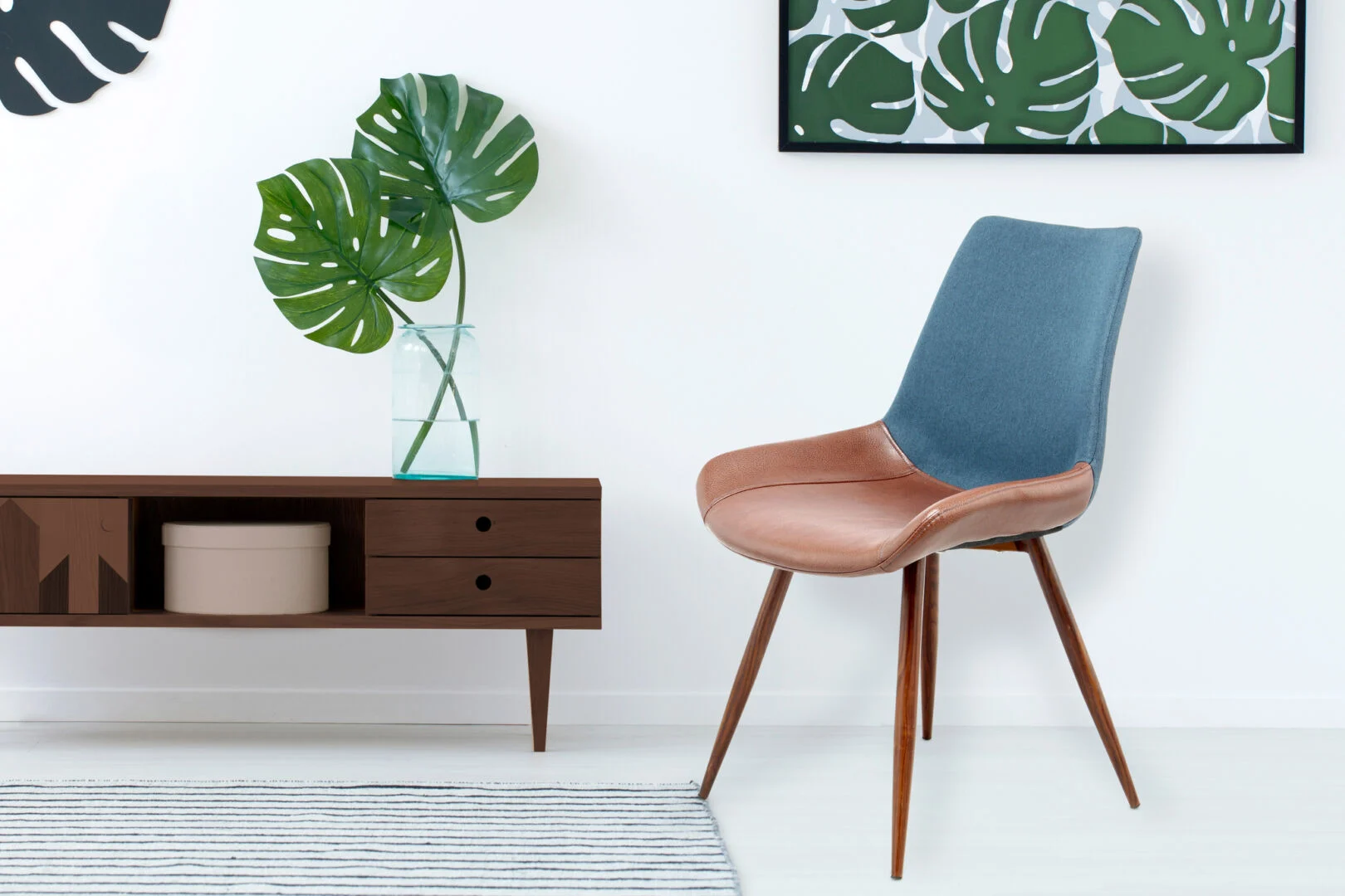 Stoel Evergreen Donkerblauw Bruin: Blauwe en bruine stoel van Nieuwe Sfeer naast een houten console met monstera plant