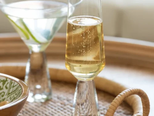 Drinkglas Naarden transparant glas, hoge slanke vorm, gevuld met mousserende drank op een serveerblad