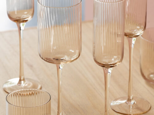 Brollan Glas Oranje drinkglazen met geribbelde wand en elegante slanke vorm op houten tafel
