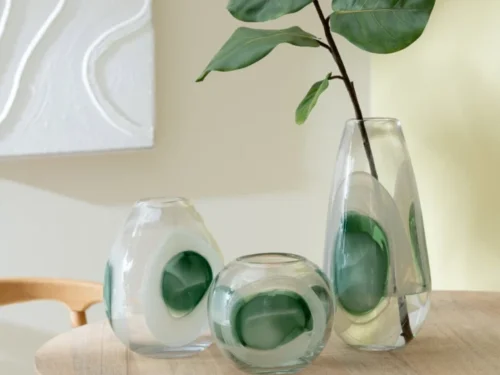 Vaas Skarros glas meerkleurig met groene accenten, gevuld met tak, op houten tafel