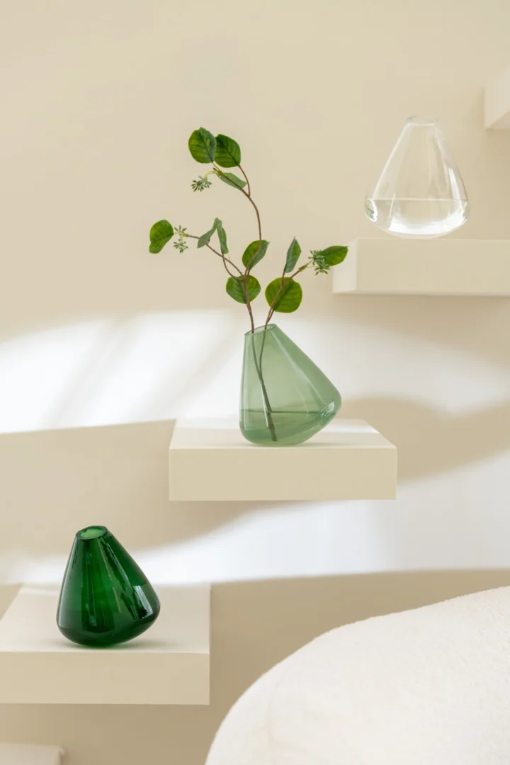 Vaas Keermin van lichtgroen glas, 13,5 cm, met slanke organische vorm op een nis in een rustig interieur