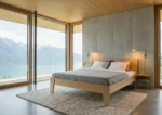 Bed Goslar 97x209 van eikenfineer met schuin hoofdbord in lichte, moderne slaapkamer met uitzicht op het meer