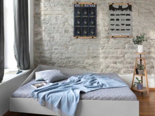 Bed Koorund in asymmetrische hoekvorm, modern grijs bed met plaid in sfeervolle slaapkamerhoek