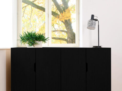 Zwart dressoir Fleimmona 160 cm met strakke deuren en slanke poten in een lichte woonkamer
