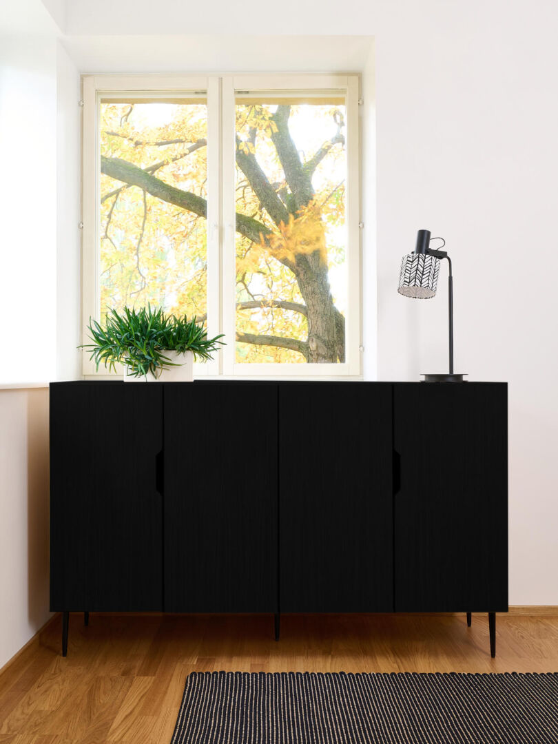 Zwarte dressoir Zeessar 160 cm met vier deuren, strakke lijnen en slanke poten in een lichte woonkamer