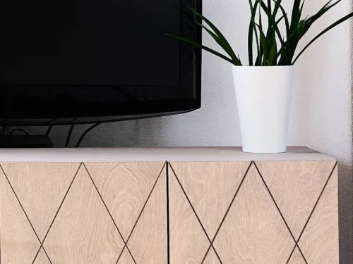 Dressoir Tirmond grijs met gegraveerde deurpatronen, afgebeeld onder tv met plant in modern interieur