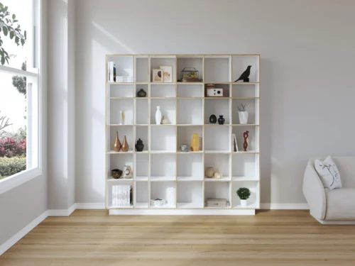 Wandplank Beistano 191 cm als witte ruimteverdeler met open vakken, gevuld met boeken, vazen en decoratie