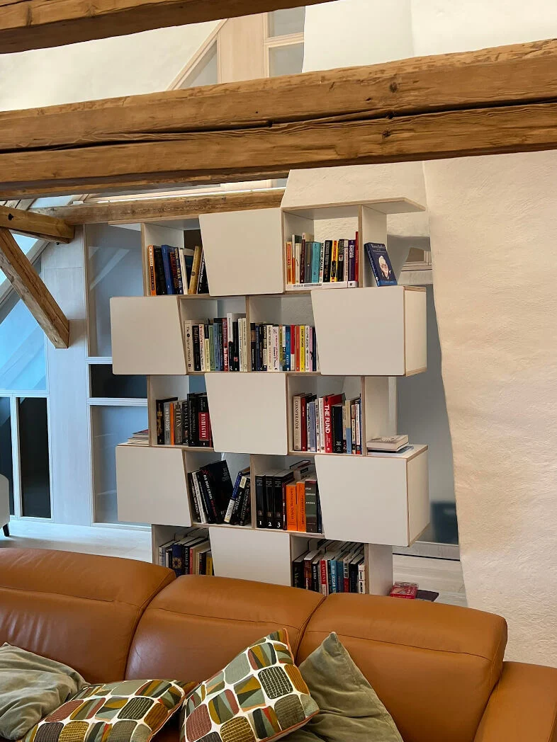 Wandplank Jusir 140 cm met witte HPL, diagonale vakken en open planken vol boeken