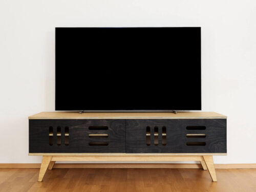 TV-meubel Grurron 120 cm met lichte eiken top, zwarte kastfronten en schuine berkenpoten onder een flatscreenTV