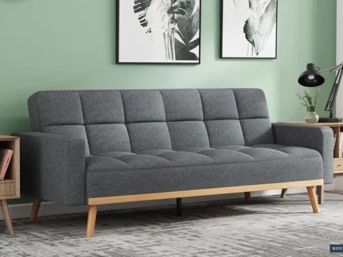 Slaapbank Nantes Grijs met gewatteerde zitting, houten poten en strakke grijze bekleding in moderne woonkamer
