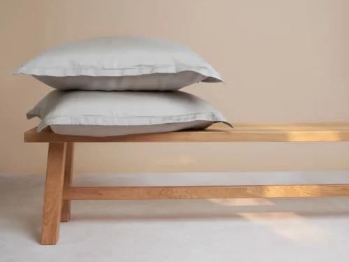 Kussenhoes Peelas taupe, zacht Tencel, 60x50 cm, op een houten bank in rustige woonstijl