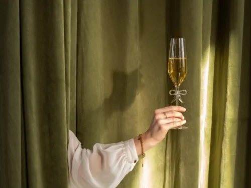Transparant Bunnin champagneglas met strakke hoge vorm, gevuld met mousserende drank in een hand gehouden