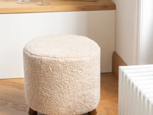 Schapenvacht Viemund Beige poef met zachte bouclélook en houten pootjes in warme woonkamerstijl