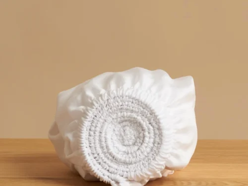 Witte Topper Skuvon van Tencel, zacht, ademend en comfortabel opgerold op houten tafel