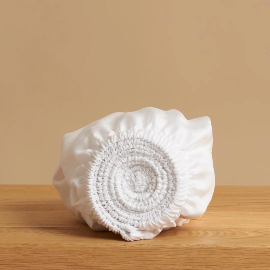 Witte Topper Skuvon van Tencel, zacht, ademend en comfortabel opgerold op houten tafel