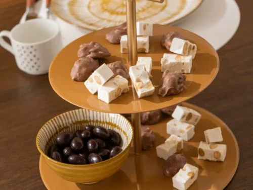 Woonaccessoire Laarrel Metaal Geel als rond etagère, gevuld met snoep en een kom chocolade op tafel
