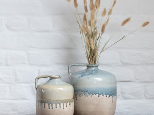 Karaf Firran keramiek beige met handgreep en rustieke blauwe glazuuraccenten op houten kast