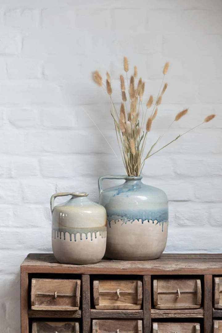 Karaf Firran keramiek beige met handgreep en rustieke blauwe glazuuraccenten op houten kast