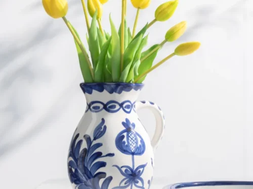 Schenkkan Kooli keramiek meerkleurig met blauw decor, gevuld met gele tulpen op tafel