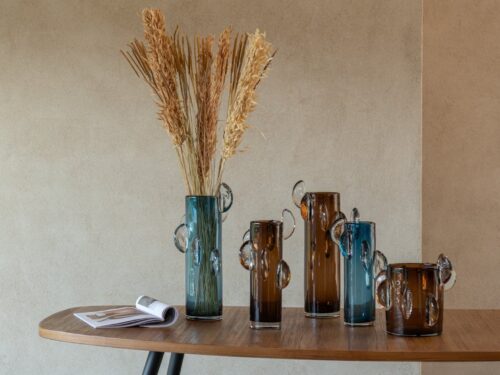 Vaas Soke Glas Bruin met strakke cilinder vorm en decoratieve glazen oren op een houten tafel