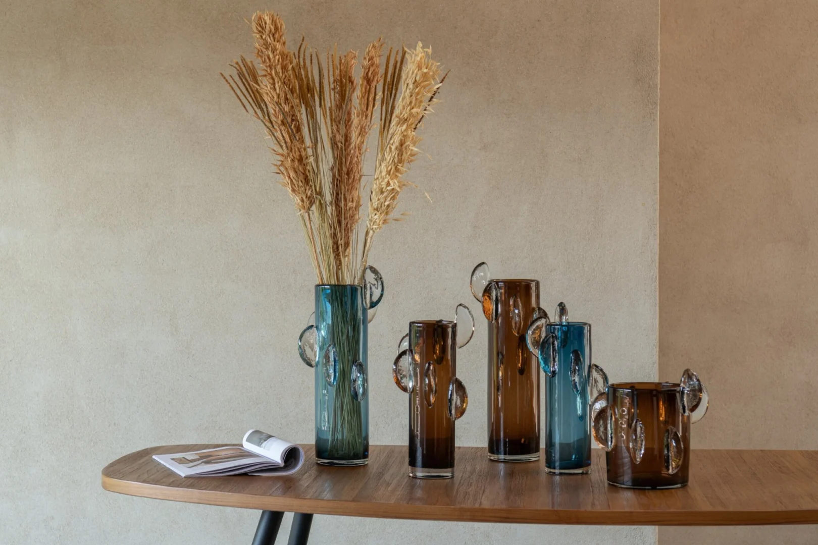 Vaas Soke Glas Bruin met strakke cilinder vorm en decoratieve glazen oren op een houten tafel
