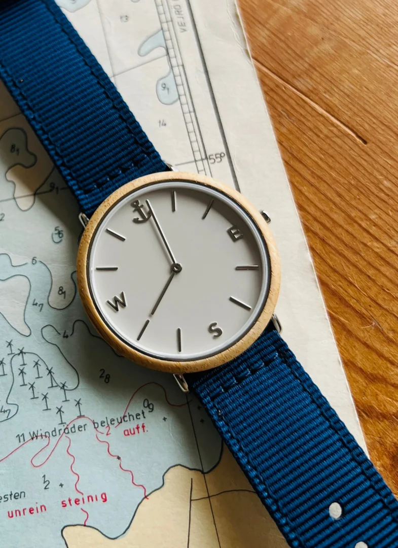 Horloge Voosesta Navy met navy band, lichtgrijze wijzerplaat en houten-look kast op kaart achtergrond